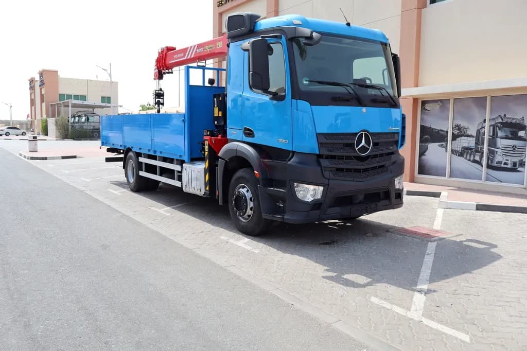 Blue boom truck with the knuckle boom crane unfolded over the bed