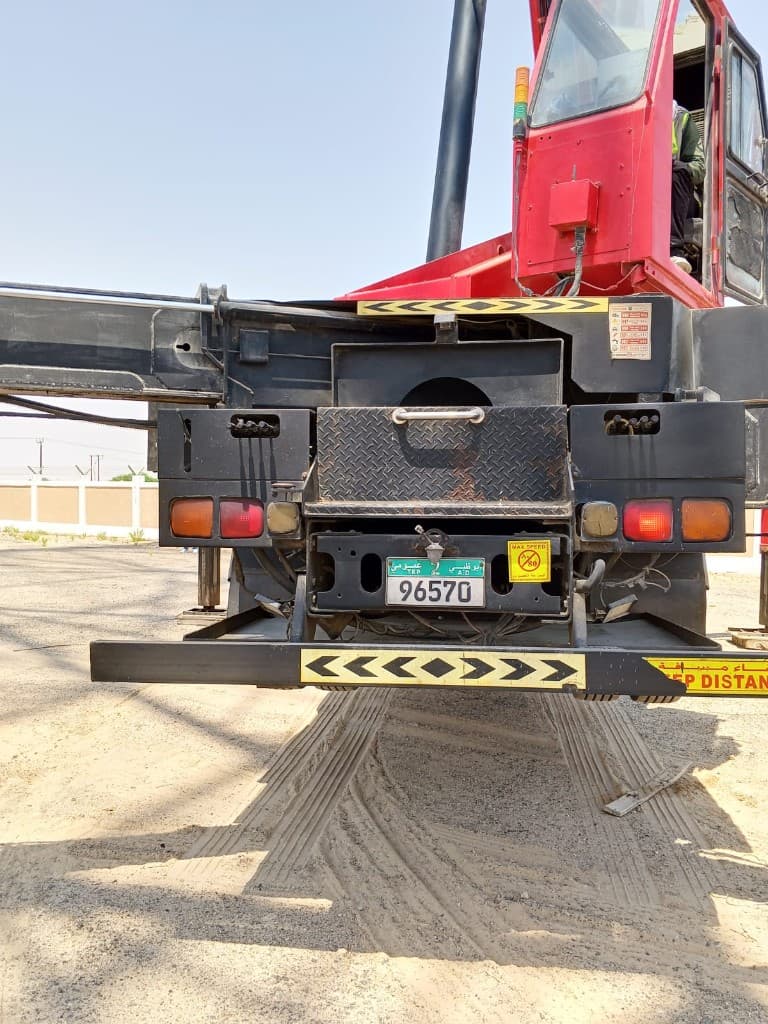 Truck-mounted manlift with the boom lowered under a lattice tower