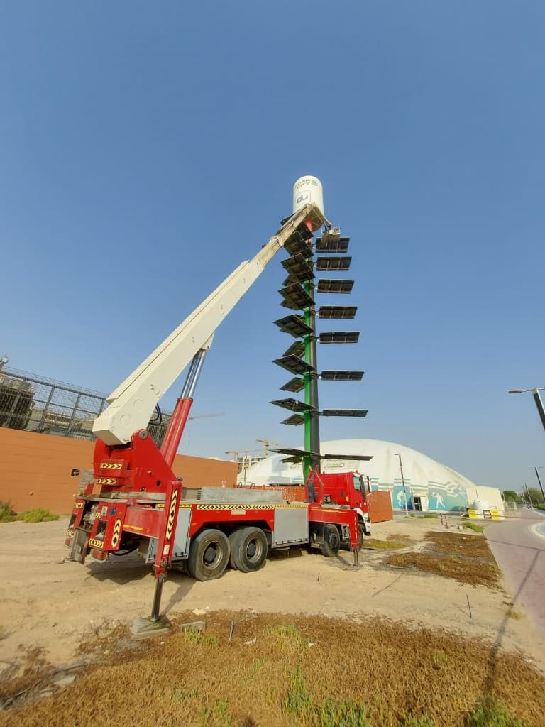 Truck-mounted manlift set up beside a solar lighting tower in Abu Dhabi